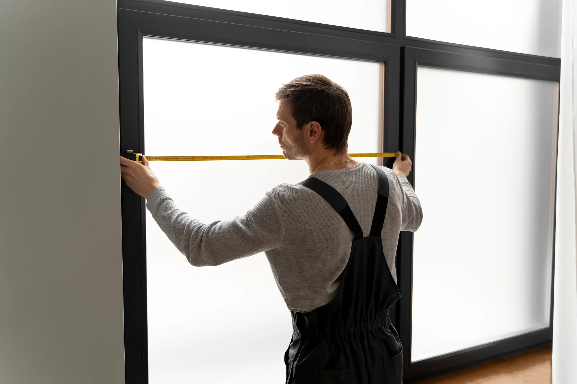Customer measuring a window with a tape measure